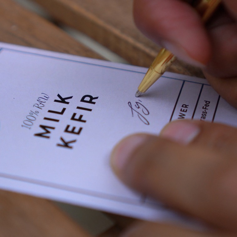 Imran signing a Milk Kefir label by hand